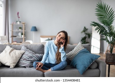 Attractive Smiling Woman Talking On The Phone At Home. Technology, Communication And Coziness Concept.