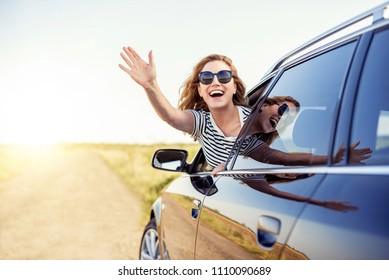 Attractive Smiling Woman Waving Her Hand From The Car Window.