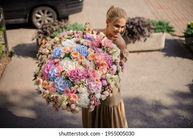 Attractive Smiling Young Blonde Woman With Beautiful Huge Bunch Of Different Flowers In Her Hands