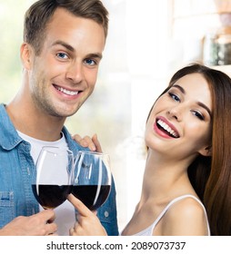 Attractive smiling young couple drinking redwine. Portrait image of caucasian models with red wine glasses in love concept. Man and woman posing together indoor. Square composition. Valentines Day.