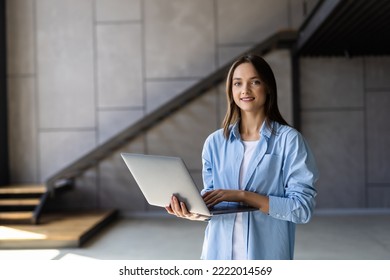 Attractive Smiling Young Woman Using Laptop Computer While Standing In A Stylish Living Room