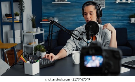 Attractive Social Media Influencer Speaking To Audience At Microphone While Tweaking Sound Using Professional Mixer. Creative Digital Content Creator Recording Podcast At Home Studio.