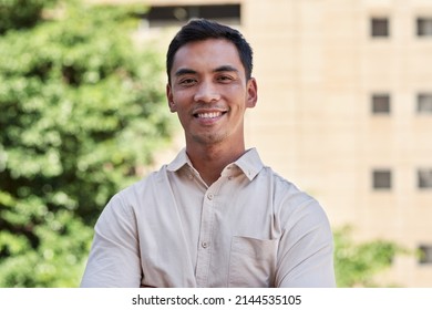 An Attractive South East Asian Man Smiles For A Portrait Outside City Building