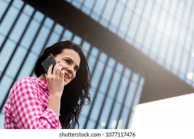 Attractive Spontaneous Woman Talking On The Phone. Authenticity And Spontaneity. Authentic Conversation Over The Phone. The Girl In Sunglasses Holds A Mobile Phone In Hand.