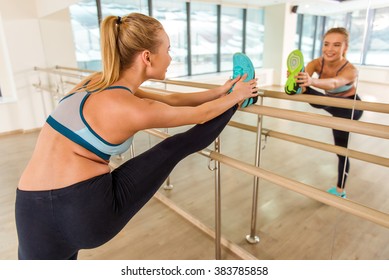 Attractive sport girl smiling and looking in the mirror while stretching the body in fitness class