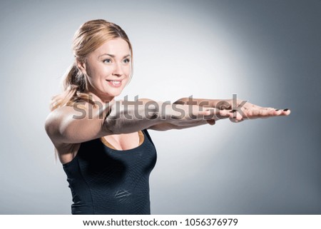 Similar – Close up front portrait of one young mid adult athletic woman in sportswear in gym over dark background, standing in boxing stance with hands and fists, looking at camera