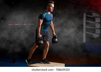 Attractive Sportsman With Kettle Bell Exercise In The Fitness Gym On The Color Smoke Background. Copy Space Area For Advertise Slogan Or Text Message. Functional Training And Crossfit Concept.