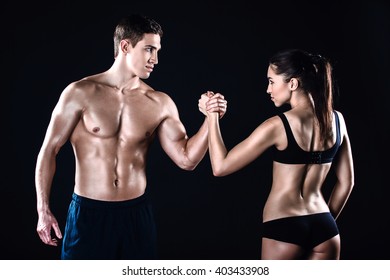 Attractive Sportsman And Woman. Studio Shot Of Young Sporty Muscular Man And Woman On Black Background