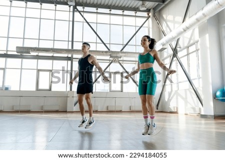 Attractive sportsmen, young girl and boy training using skipping rope in gym. ?oncept of sports, health care