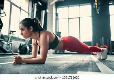 Attractive sporty woman in gym. Young perfect shaped brunette doing plank