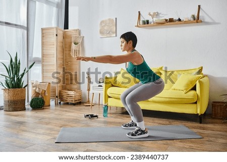attractive sporty woman in sportswear squatting with hands in front her, fitness and sport. tattoo translation: sugar-free or no sugar