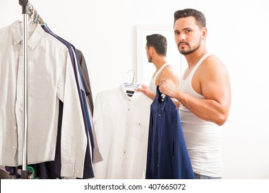 Attractive And Strong Young Man Choosing Between To Shirts To Wear While Getting Dressed In A Dressing Room