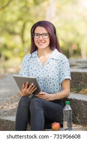 Attractive student girl studying with tablet on a natural background. Modern electronics concept.
