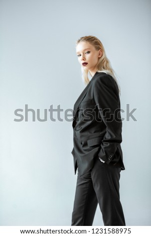 attractive stylish girl posing in black formal wear isolated on grey