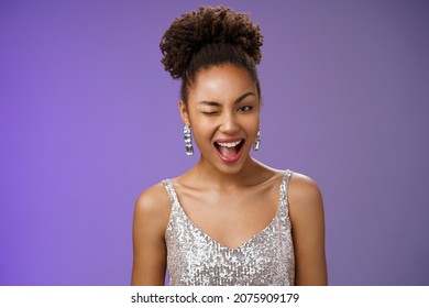 Attractive stylish wealthy african american woman in luxurious earrings silver dress winking asssuring everything ok guarantee your secret safe smiling devious have excellent plan, blue background
