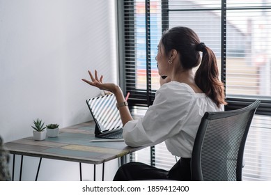 Attractive and successful asian businesswoman working in modern office, talking on phone with client at their desk. - Shutterstock ID 1859412400