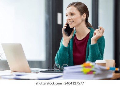 Attractive successful elderly businesswoman working in modern office, making phone call to potential client, having nice conversation, sitting at desk in front of open laptop - Powered by Shutterstock