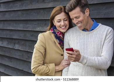 Attractive, Successful And Happy Middle Aged Man And Woman Couple Together Outside Using Mobile Cell Phone