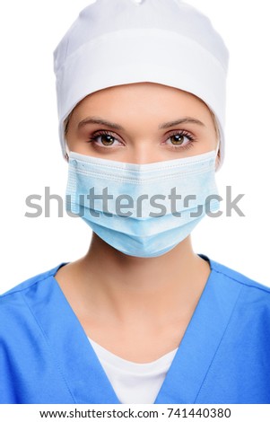 attractive surgeon in medical cap and mask, isolated on white