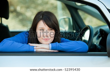 Attractive teen girl smiling at the camera sitting in her car outdoor