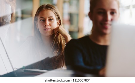 Attractive teenage girl sitting in classroom and thinking. Young people studying in university classroom. - Shutterstock ID 1115087834