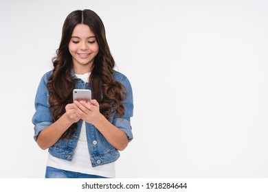 Attractive teenage girl using mobile phone in casual attire isolated over white background