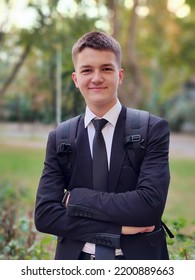 Attractive Teenage Guy Smiling With A Backpack Goes To Study On The Street To School Or University. He Is Smiling. Background Is Blurred. Front View