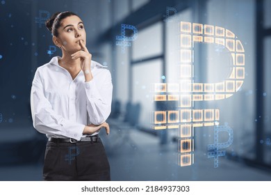 Attractive thoughtful young european businesswoman with creative glowing Russian ruble hologram on blurry office interior background. Digital money and online banking concept. Double exposure