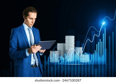 Attractive thoughtful young european man using tablet with creative hologram with growing chart and stacked coins on dark background. Financial growth and investment concept - Powered by Shutterstock