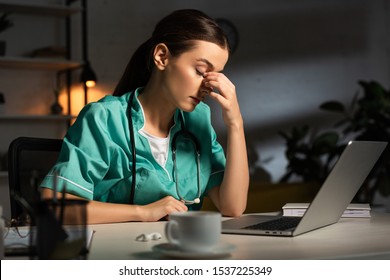 attractive and tired nurse in uniform sitting at table during night shift - Shutterstock ID 1537225349