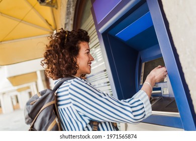Attractive tourist woman uses a credit card near the ATM. The concept of tourism, travel, leisure.