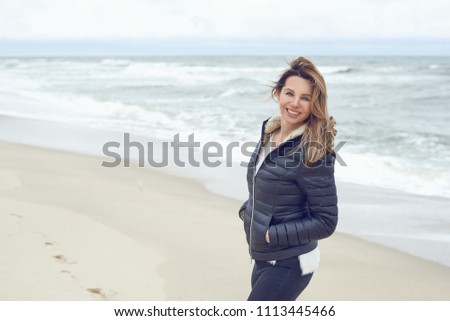 Similar – Woman walking on a beach on a cloudy day