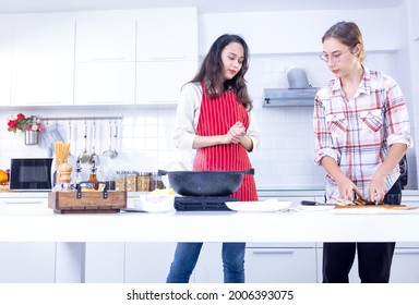 Attractive Two Smile Women Is Cooking In The Modern Kitchen, Two Friends Having Fun, Sisters Cooking Together.