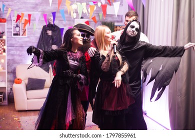 Attractive Vampire Woman Singing At A Halloween Party With Her Friends.