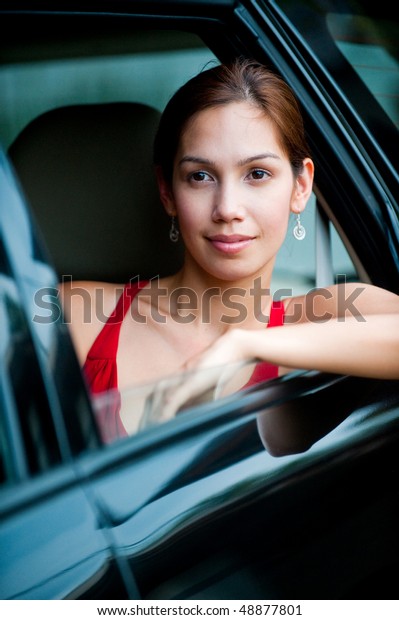 An attractive well-dressed lady stepping out of\
a stylish car outdoors