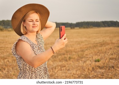 Attractive White European Woman In Dress And Hat Making Selfie At Evening Time Outdoors.