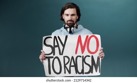 An Attractive White Man In A Blue Hoodie Is Standing And Showing A Poster Against Racism 