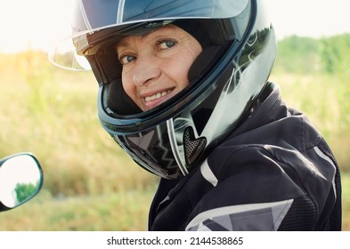 Attractive Woman 60 Years Old In A Motorcycle Helmet Looking At The Camera. Close-up Portrait.