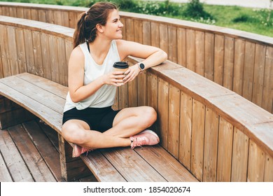 Attractive woman after running holding coffee or tea and relaxing. Resting Runner.  - Powered by Shutterstock