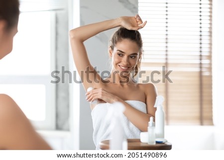 Attractive Woman Applying Antiperspirant Roll On Armpits For Freshness And Sweating Prevention Standing In Modern Bathroom At Home. Female Caring For Armpits. Selective Focus