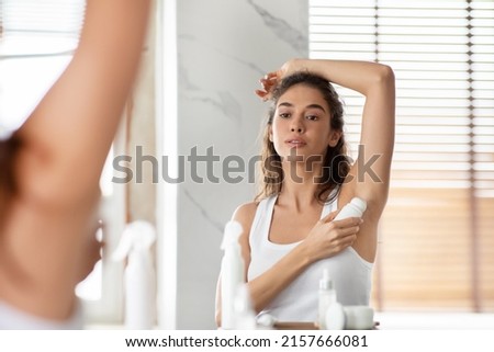Attractive Woman Applying Antiperspirant Underarms For Sweat Protection Standing Raising Arm Posing In Modern Bathroom At Home. Armpits Skin Care And Hygiene Routine Concept