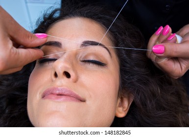 Attractive Woman In Beauty Salon On Facial Hair Removal Eyebrows Threading Procedure