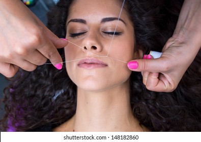 attractive woman in beauty salon on facial hair removal  threading procedure
