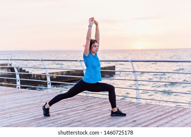 Attractive Woman In Blue Shirt Doing Deep Lung With Hans Up Seashore At Sunrise