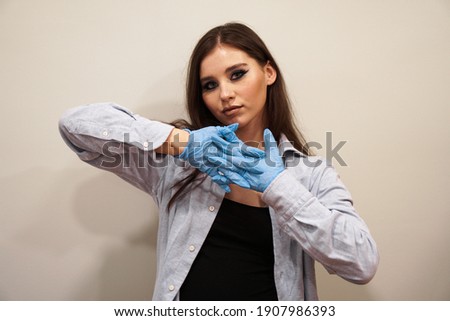 Attractive woman with blue stylish makeup with latex gloves in beauty studio