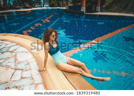 Attractive woman in blue swimsuit chilling at poolside
