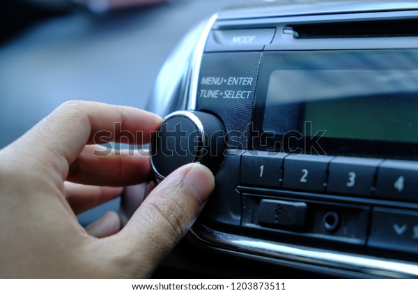 attractive woman in\
car driver seat adjusting radio, hand pressing phone button on\
steering wheel in the\
car.