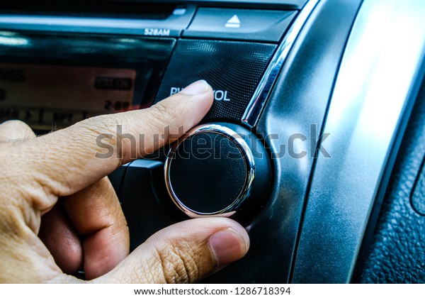 attractive woman in\
car driver seat adjusting radio, hand pressing phone button on\
steering wheel in the\
car.
