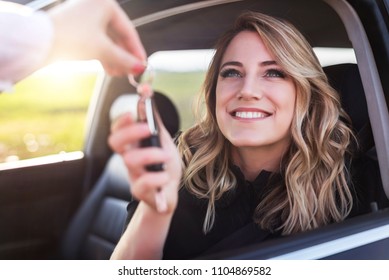 An Attractive Woman In A Car Gets The Car Keys. Rent Or Purchase Of Auto - Concept.