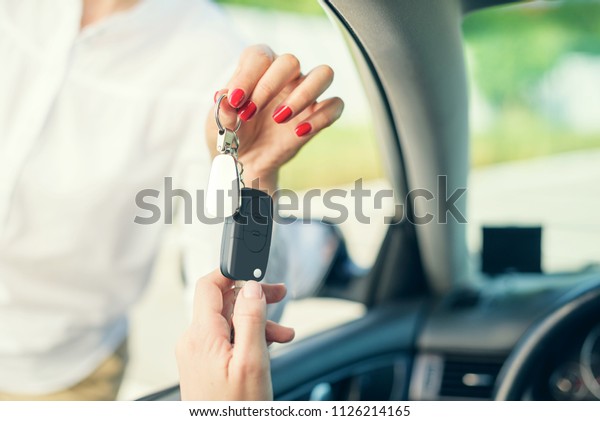 An attractive woman in a car gets the car\
keys. Rent or purchase of auto -\
concept.